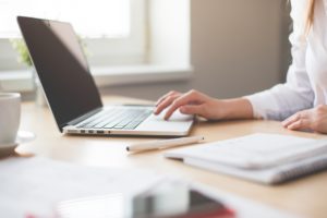 Woman working on laptop with notebook beside her