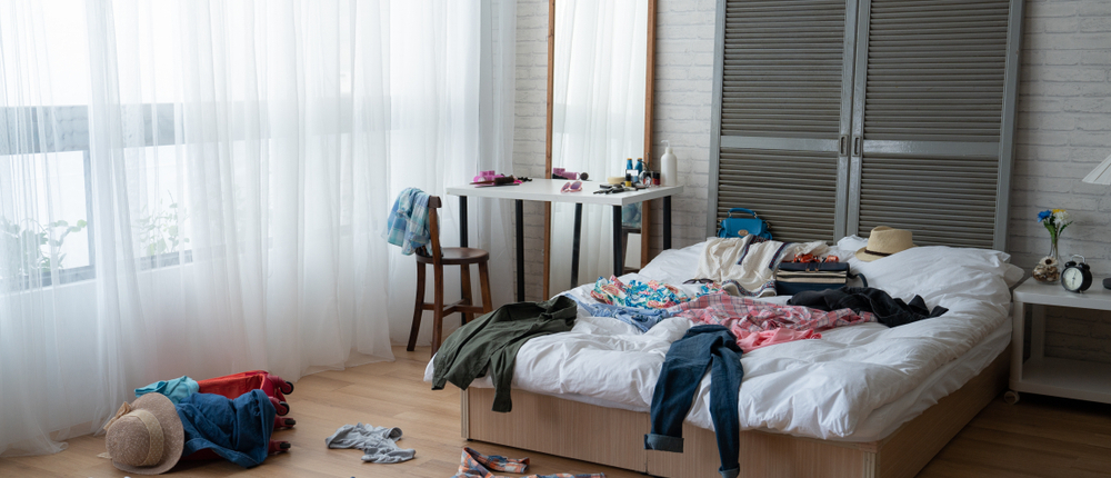 Modern,Bright,Bedroom,With,Messy,Clothes,Scatter,On,White,Bed