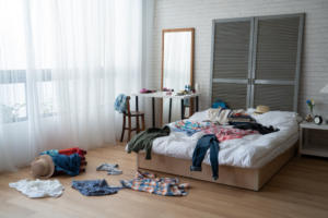 Modern,Bright,Bedroom,With,Messy,Clothes,Scatter,On,White,Bed