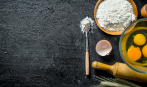 Flour with eggs in a bowl on black rustic background