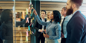 group of business people putting sticky notes on a glass wall